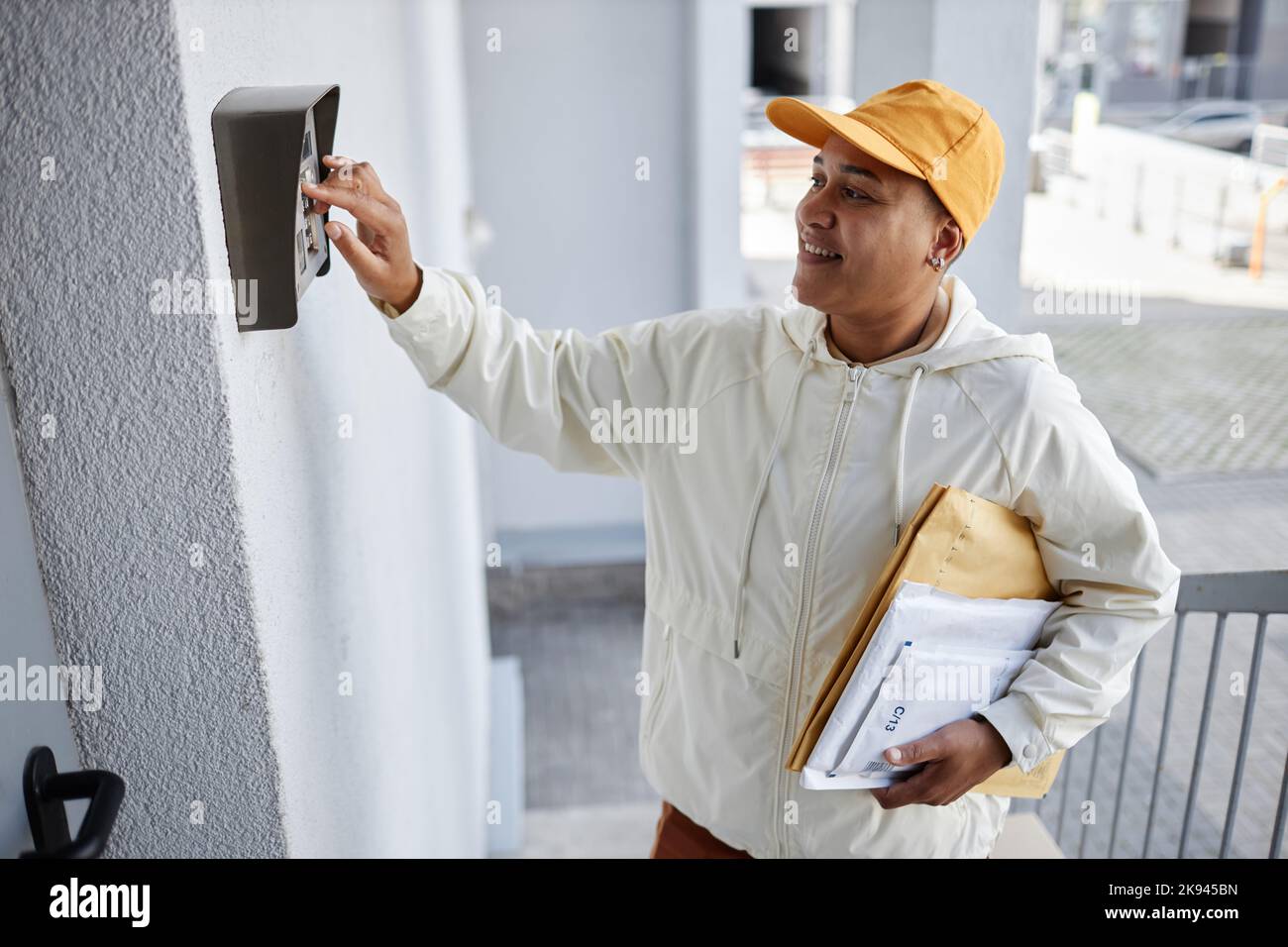 Seitenansicht Porträt einer lächelnden Frau, die Pakete lieferte und klingelte Stockfoto