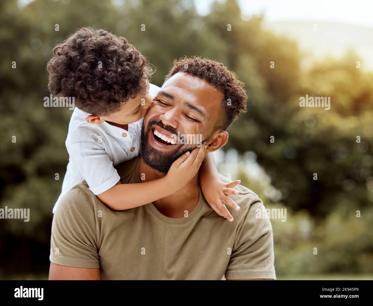 Vater, Kuss und Junge Kind umarmen glücklich in der Natur mit Qualität Zeit zusammen im Freien. Glück, Lachen und Familienliebe von einem Vater und Kind in einem Stockfoto