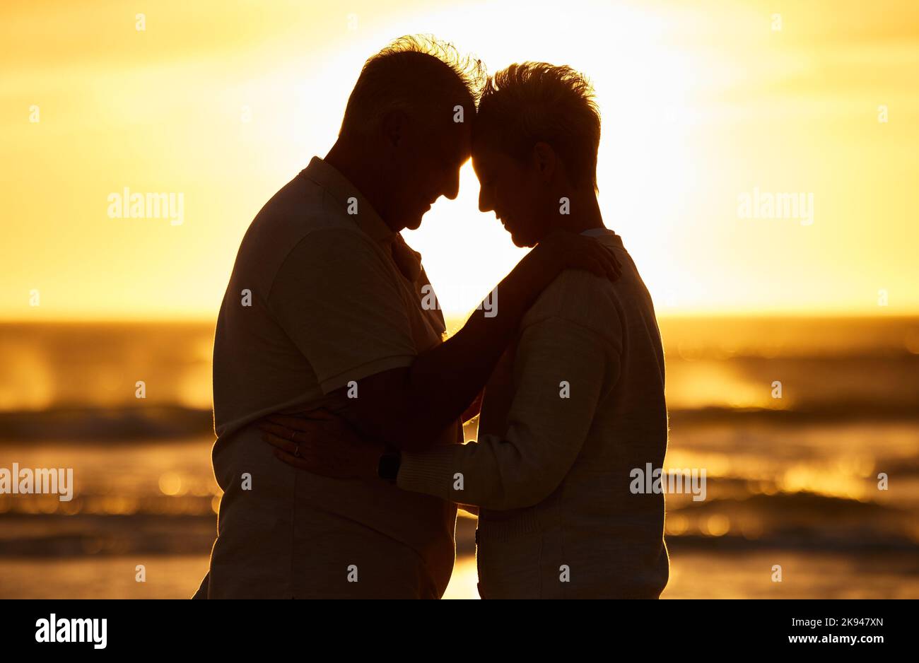 Paar, ältere Menschen und Silhouette am Strand mit Umarmung im Sonnenuntergang, Abend oder Dämmerung durch Wasser, Wellen oder Horizont zusammen. Senior, Mann und Frau am Meer, Meer Stockfoto