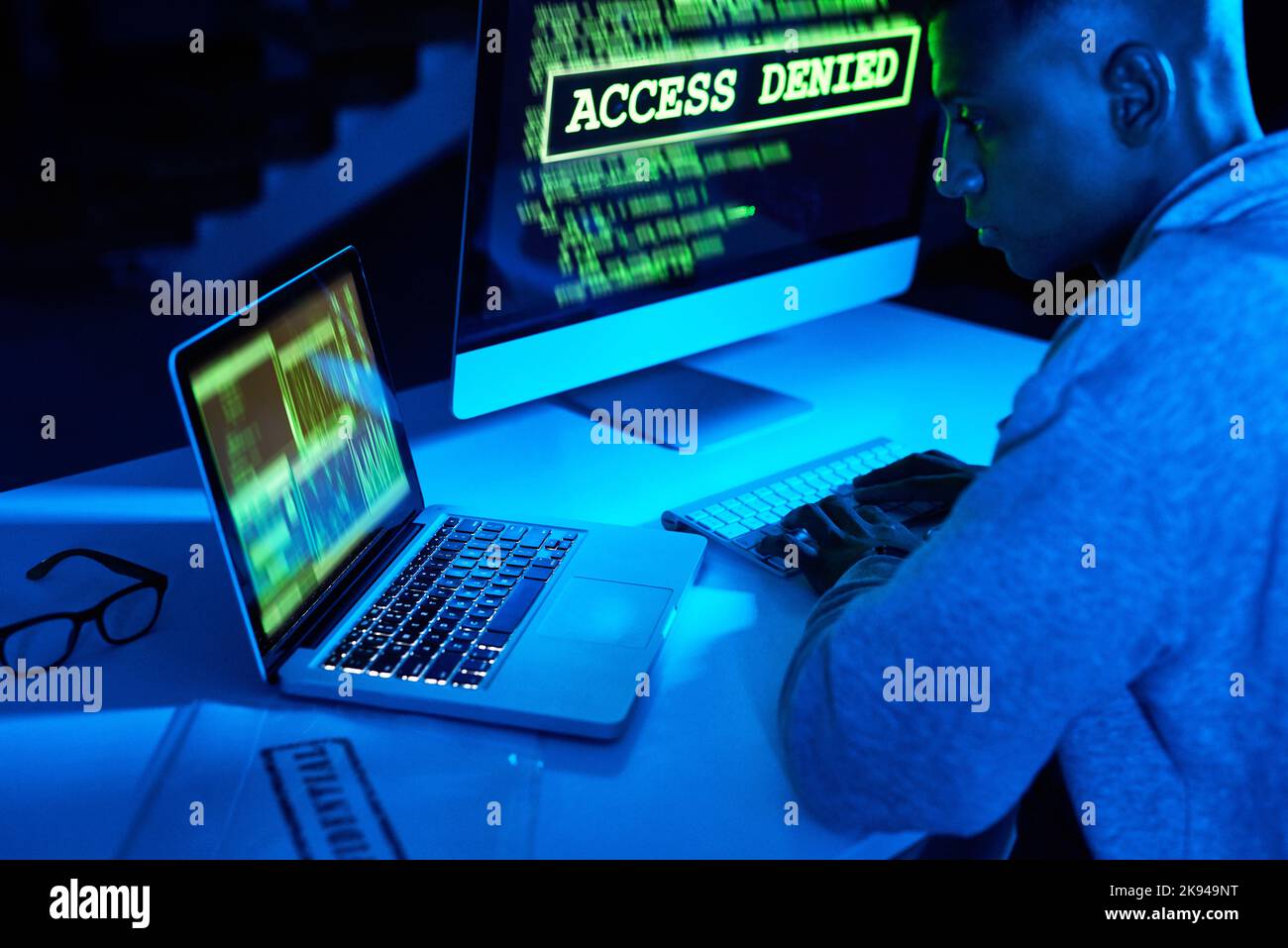 HES wird es bald knacken. Ein junger männlicher Hacker, der im Dunkeln einen Computercode knackt. Stockfoto