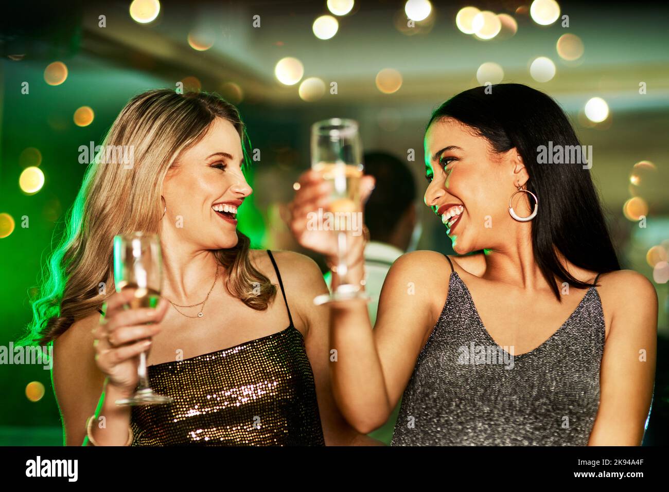 Sie wissen, wie man zwei fröhliche junge Frauen bei einem Drink Viel Spaß., während sie auf der Tanzfläche eines Clubs in der Nacht tanzen. Stockfoto