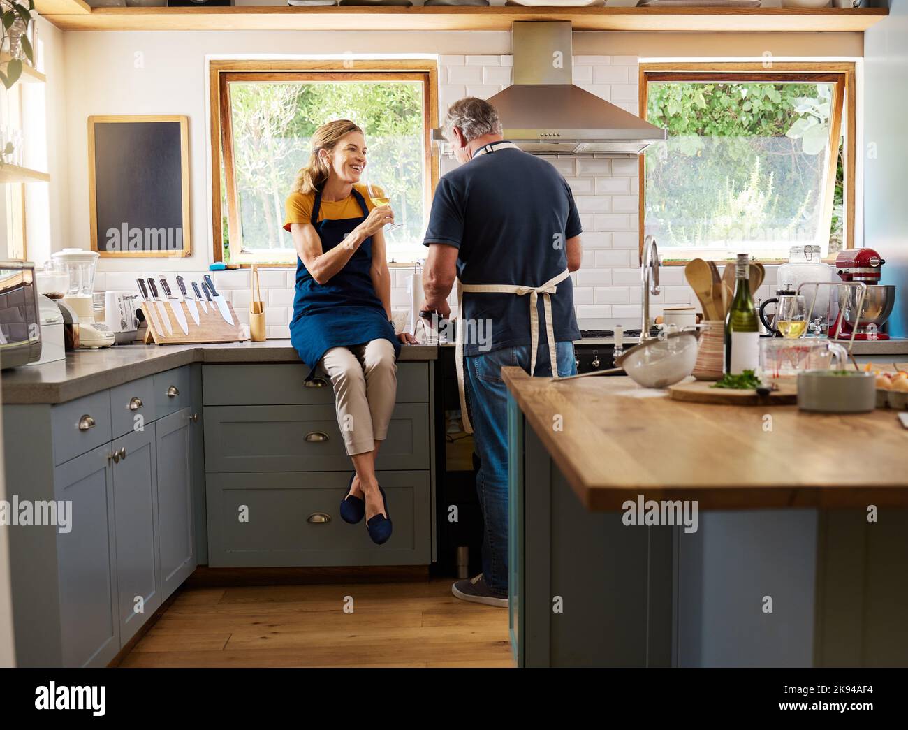 Paar, Wein und Kochen in der Küche, glücklich und reden während der Bindung, Gespräch und zu Hause. Senior, Mann und Frau im Ruhestand mit Glas, Essen und Stockfoto