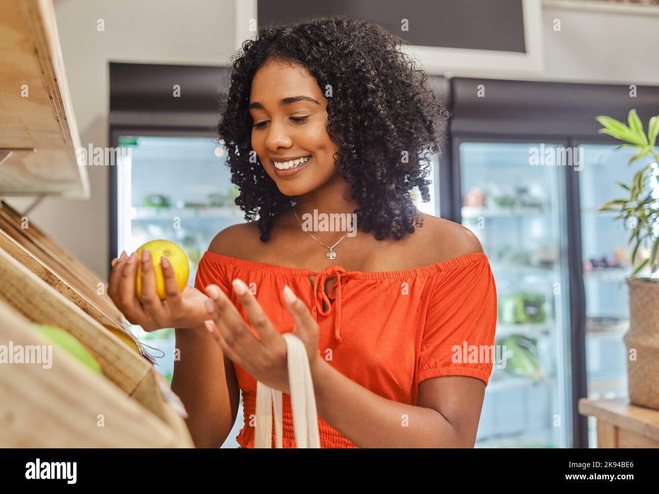 Lebensmittelgeschäft, Einkaufen und Orange mit einer schwarzen Kundin in einem Lebensmittelgeschäft für den Konsum. Lebensmittel, Supermarkt und Einzelhandel mit einer Verbraucherin Stockfoto