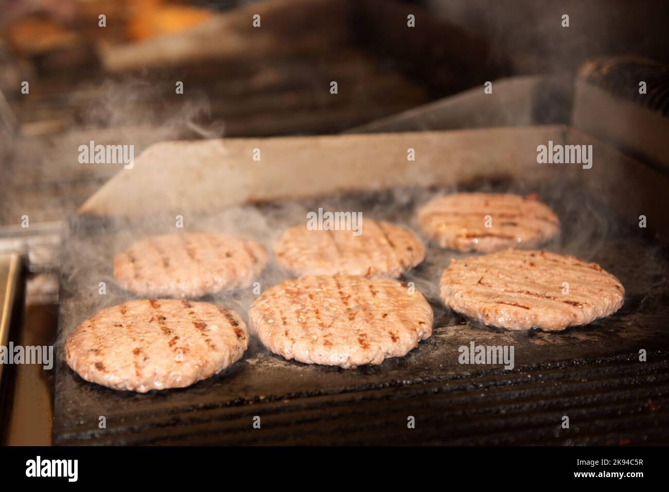 Auf dem Grill liegen brennende, frische Burger. Stockfoto