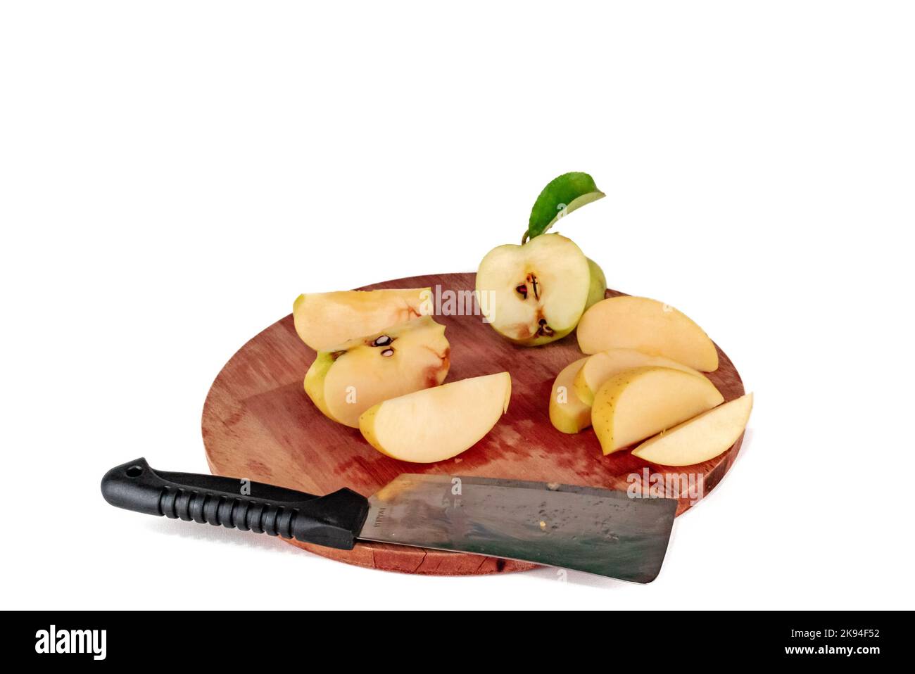 Gelbe Apfelscheiben auf einem hölzernen Schneidebrett geschnitten. Äpfel, die mit einem Spaltmesser oder einem halbgoldenen Schneidemesser geschnitten werden, köstlich in Scheiben geschnittenes, grünes Blatt. Stockfoto