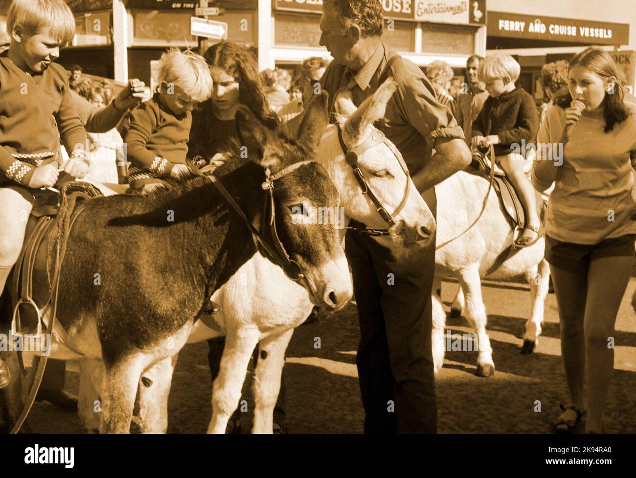 Vintage New Brighton 1968, Wallasey, Merseyside. Eselreiten am Meer, Kinder auf Eseln. Sepia-Bild, Zahlung wird genommen Stockfoto