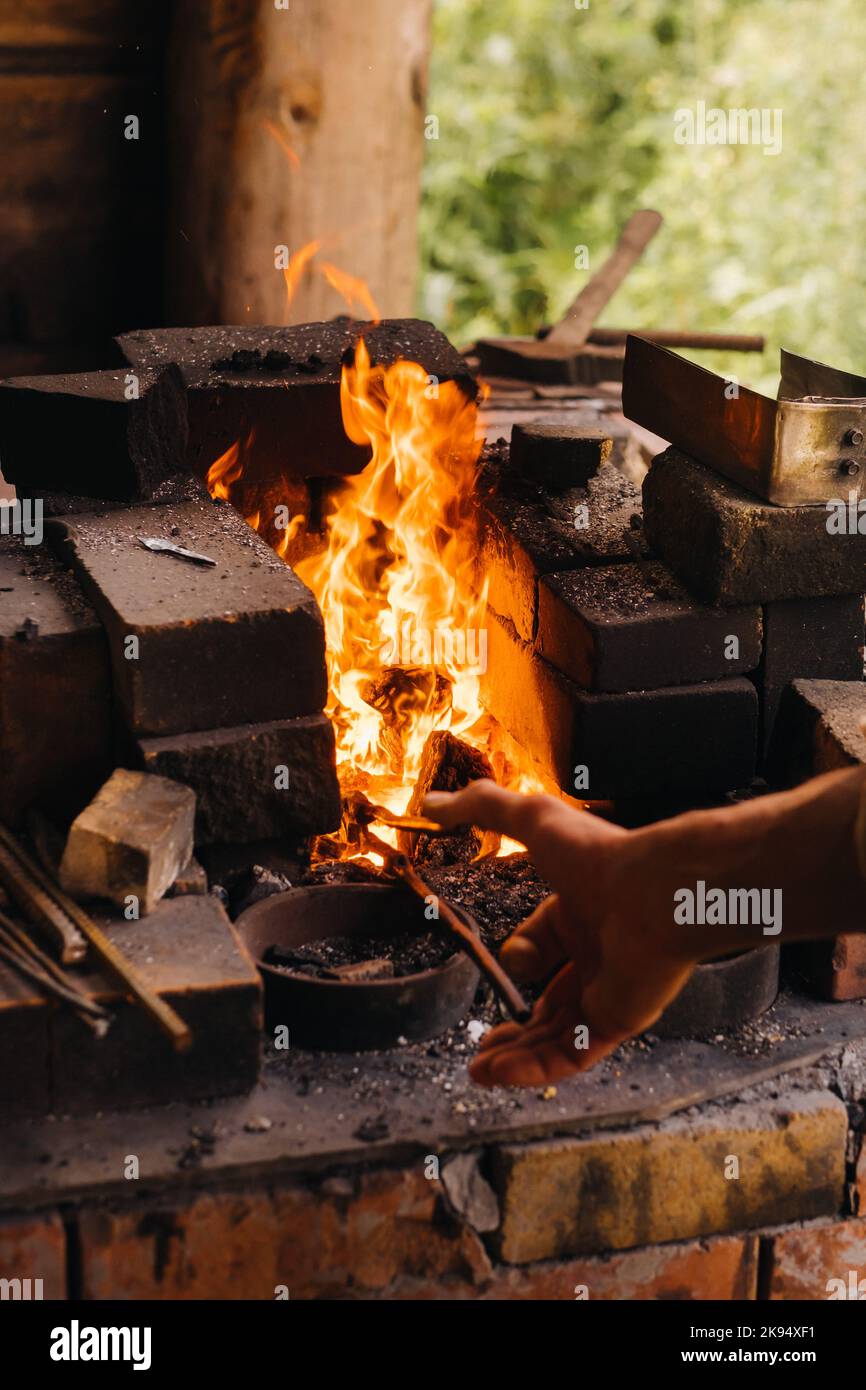Ein Schmied härtet Stahl bei hohen Temperaturen in einem hausgemachten Ofen im Dorf aus Stockfoto