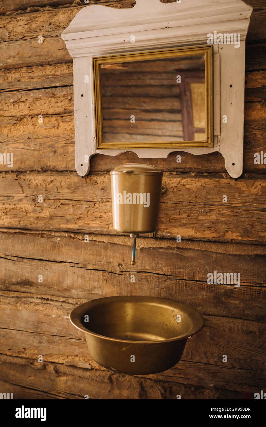Vintage-Aufnahme eines alten Metallwaschbeckens und Spiegels in einem Holzhaus im Dorf Stockfoto