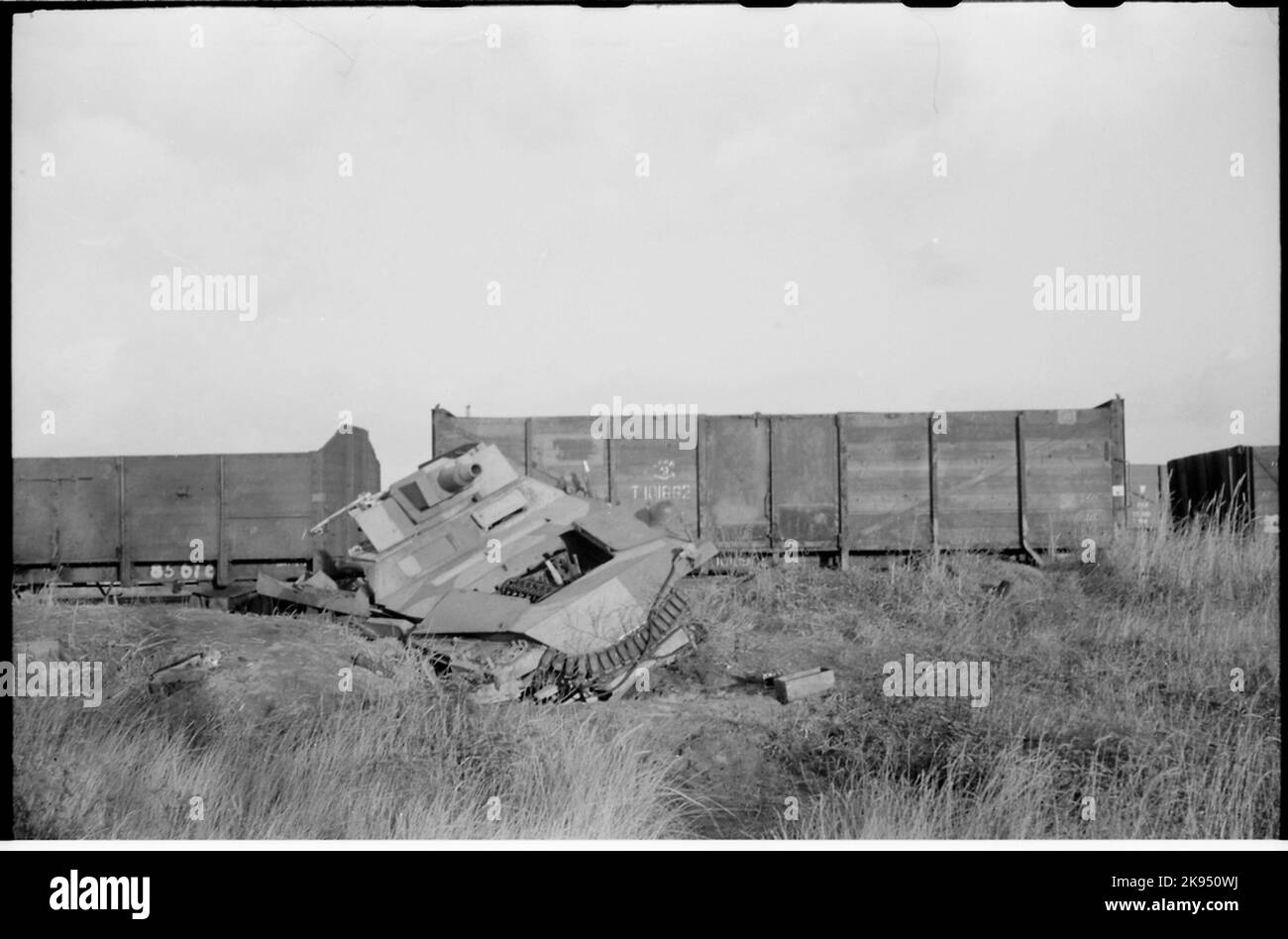Die Überreste eines zerstörten Panzerwagens vor Güterwagen. Stockfoto