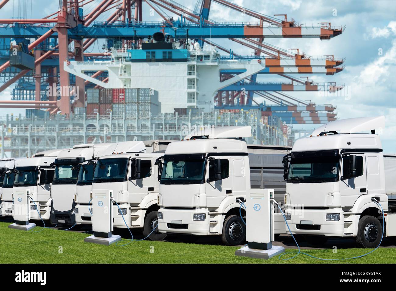 Elektro-Lkw im internationalen Seehafen vor dem Hintergrund eines mit Containern beladenen Schiffes. Stockfoto