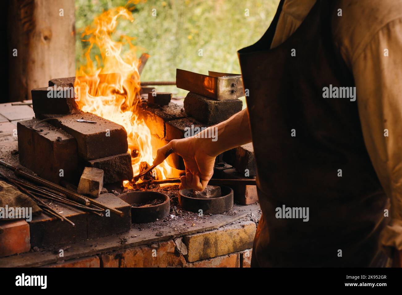 Ein Schmied härtet Stahl bei hohen Temperaturen in einem hausgemachten Ofen im Dorf aus Stockfoto