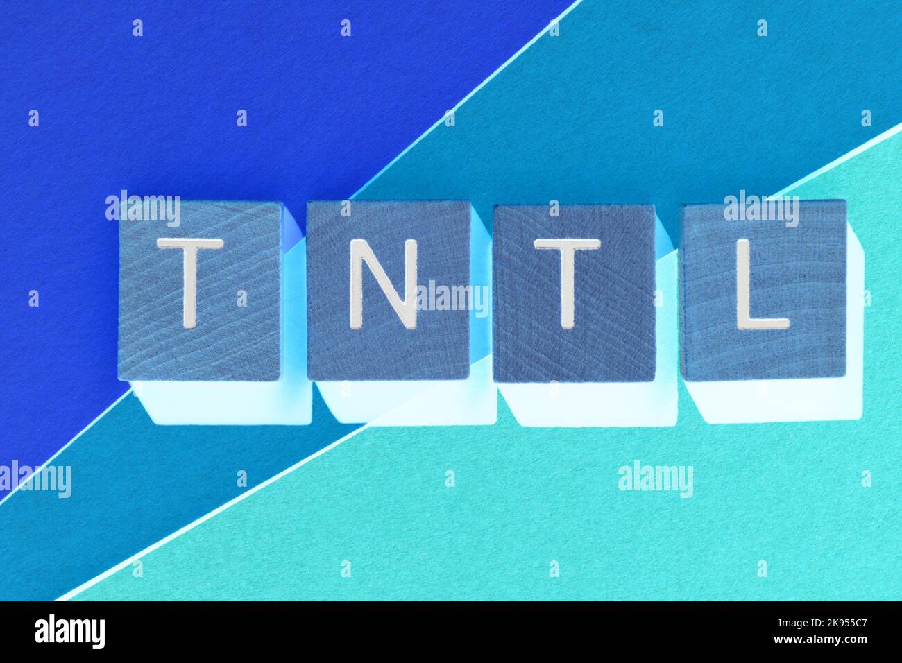 TNTL, Abkürzung für den Versuch, nicht in hölzernen Buchstaben zu lachen, die auf blauem Hintergrund isoliert sind Stockfoto