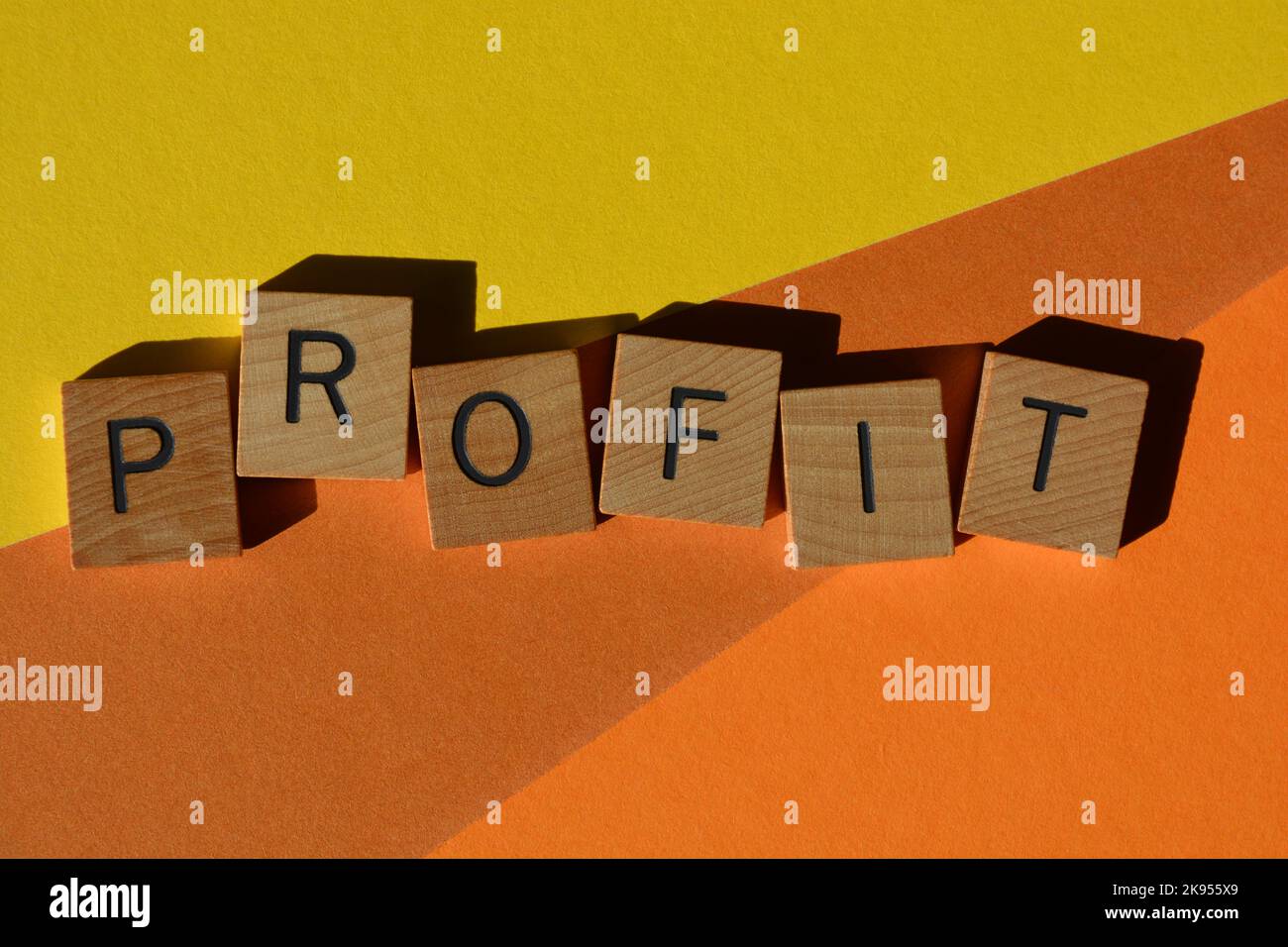 Profit, Wort in Holzbuchstaben isoliert auf orangefarbenem und gelbem Hintergrund Stockfoto