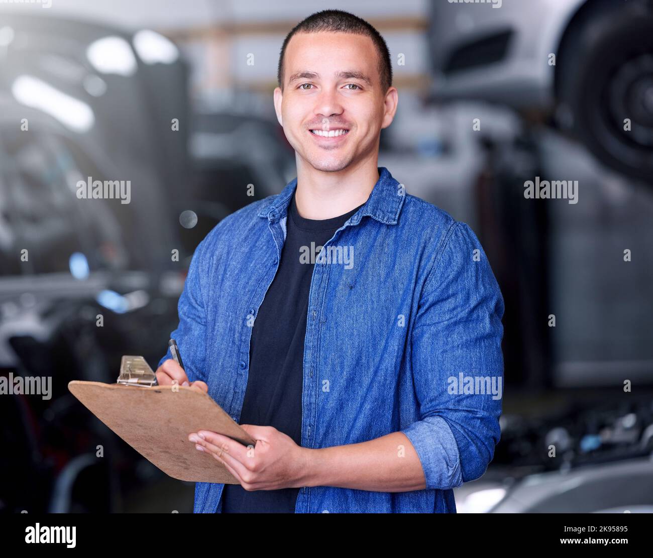Mann, Clipboard Schreiben und Maschinenbauingenieur in der Werkstatt, Autoindustrie und Autowerkstatt. Porträt, Lächeln und glückliche Automobilproduktion Stockfoto