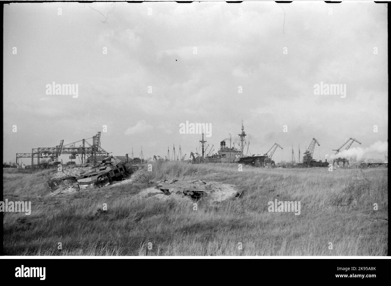 Schiffe im Hafen von Danzig. Im Vordergrund sind die Überreste eines ruinierten Panzerwagens zu sehen. Stockfoto