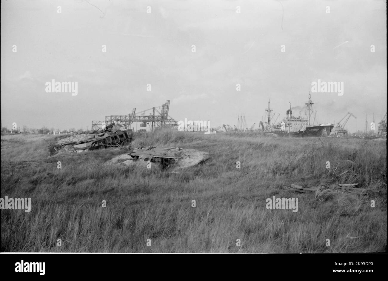 Schiffe im Hafen von Danzig. Im Vordergrund sind die Überreste eines ruinierten Panzerwagens zu sehen. Stockfoto