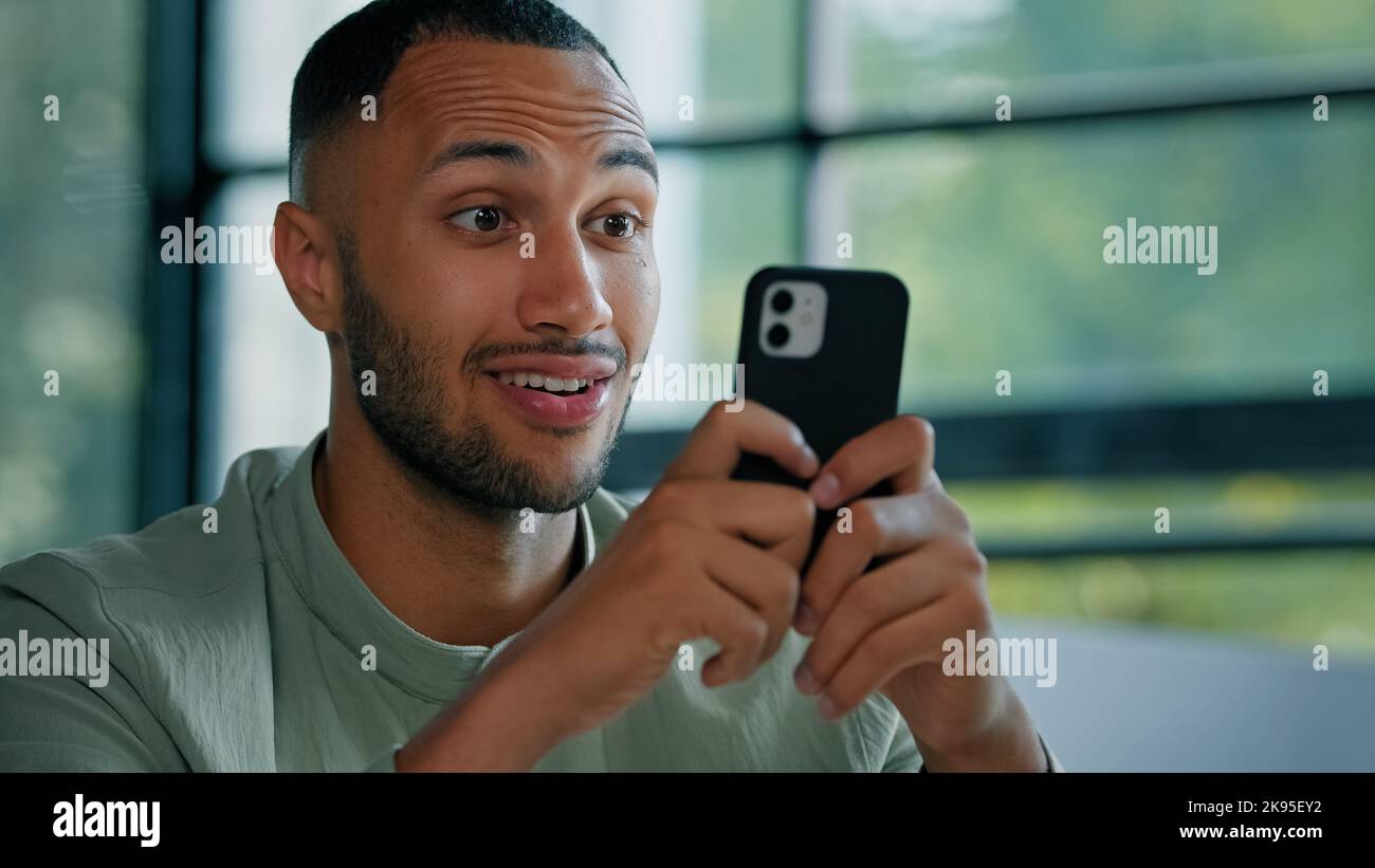Nahaufnahme männlich Mann afrikanischer Geschäftsmann Kerl Unternehmer suchen Handy lesen Nachrichten E-Mail-Nachricht Angebot Ziel Leistung erstaunt Wunder schockiert Stockfoto