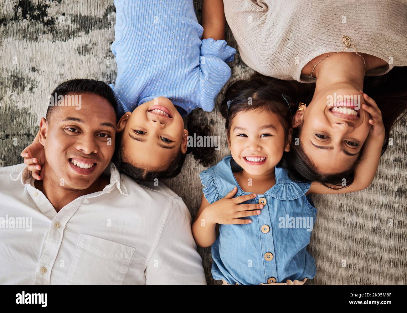 Glückliche Familie, Liebe und Porträt auf dem Boden von Kindern und Eltern im Wohnzimmer von oben zu verbinden. Gesicht, Familie und Mädchen lächeln, entspannen und verbinden sich mit Stockfoto