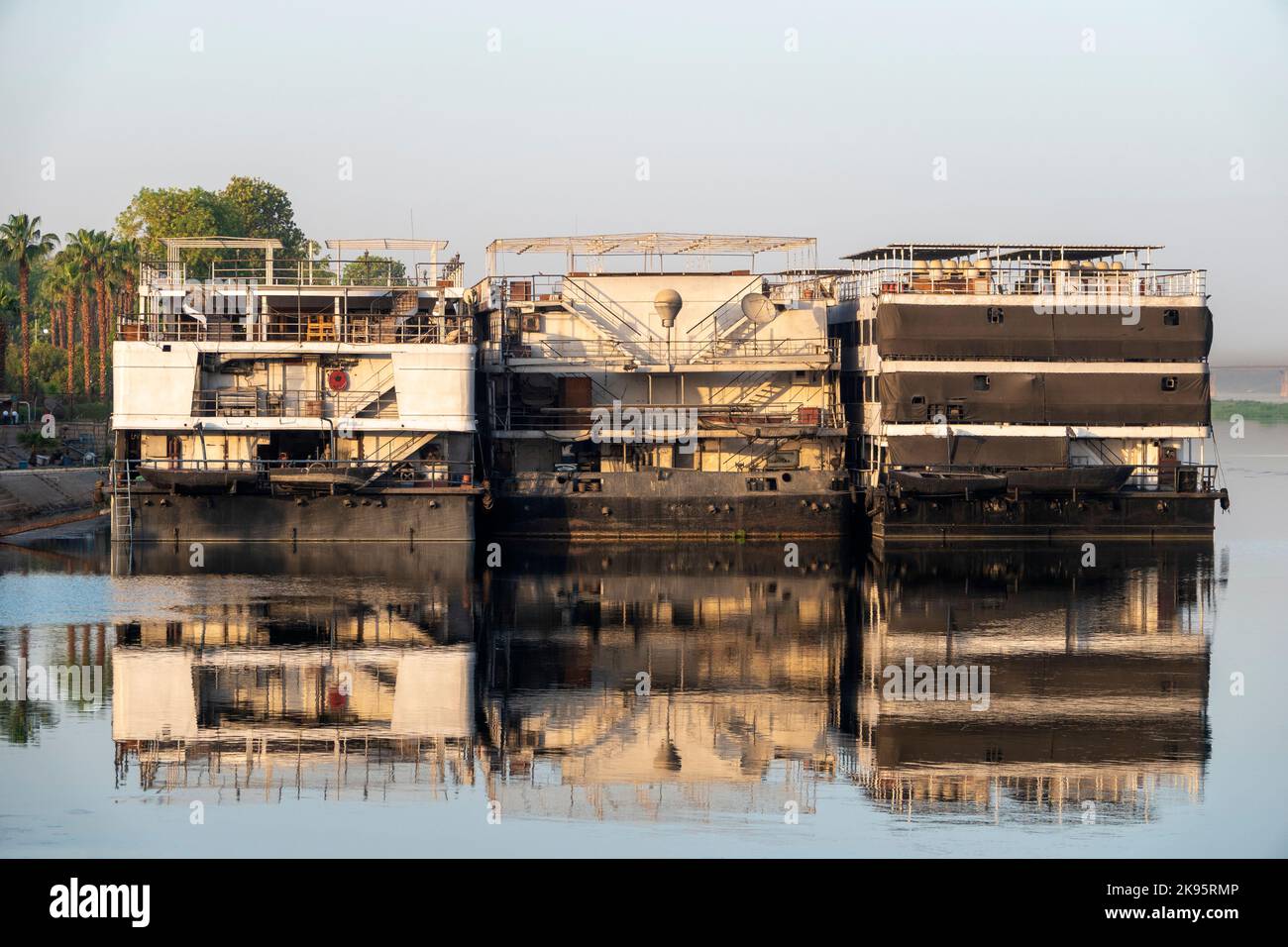 Fernaufnahme des hinteren Endes der Nilkreuzfahrtschiffe, die sich im Nil spiegeln Stockfoto