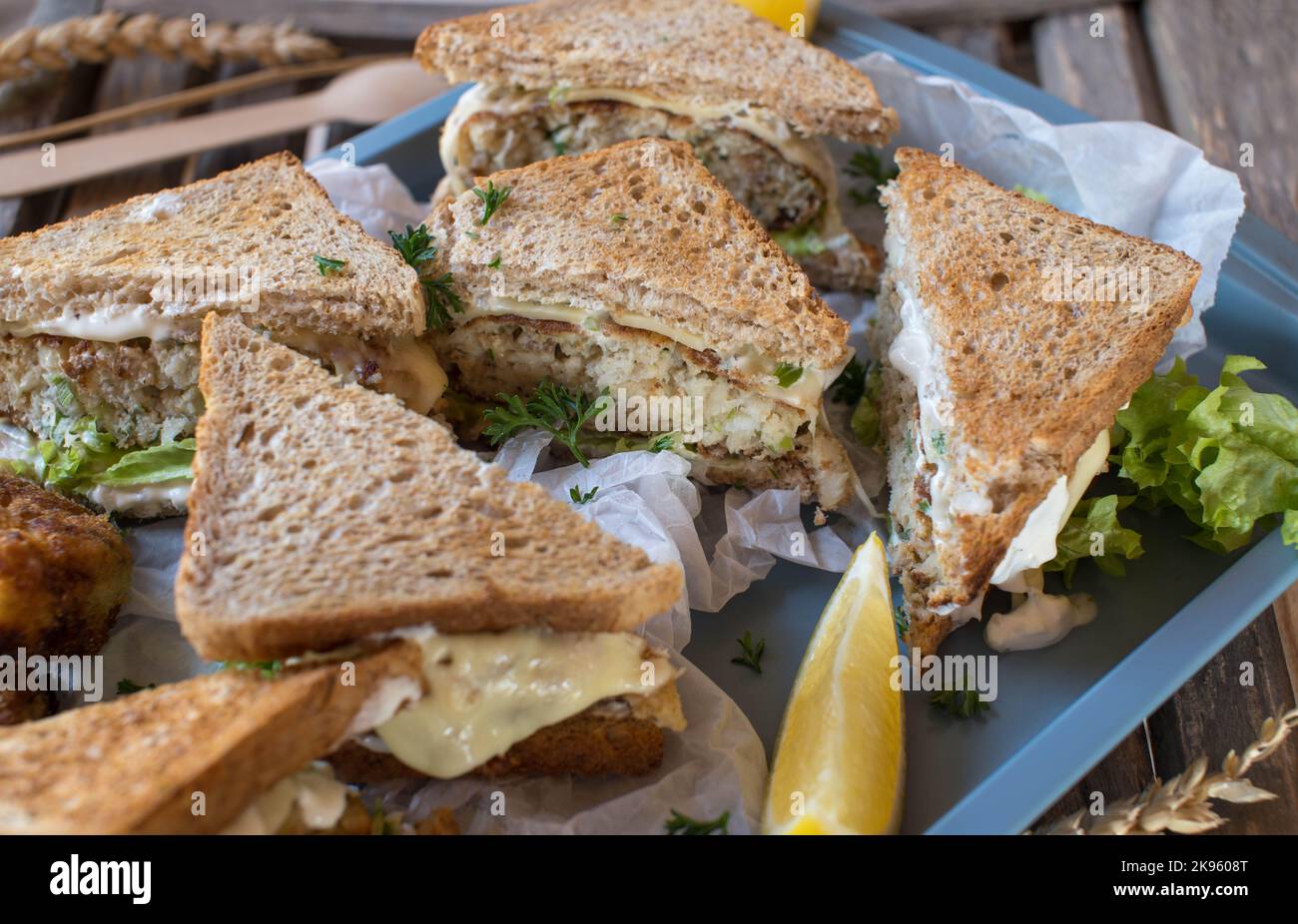 Fischkuchen-Sandwiches mit Vollkorntoast, Käse, Tartaresauce und Salat Stockfoto