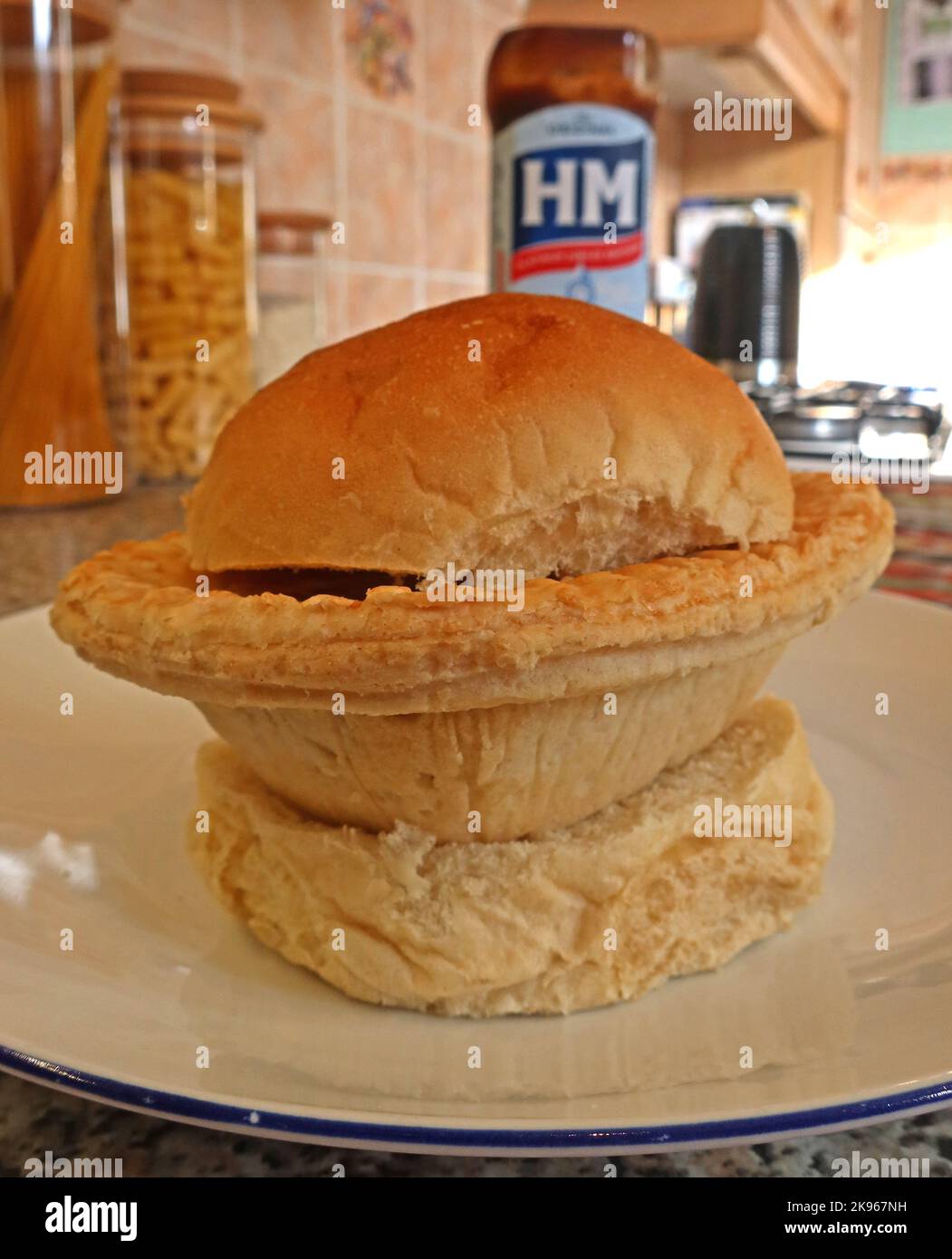 Wigan Lancashire Pie Burger, Steak- oder Fleischpastete auf einem Muffin mit Ofenboden, mit HP Sauce Bottle – nordwestlich des britischen Komfortgerichts, Großbritannien Stockfoto