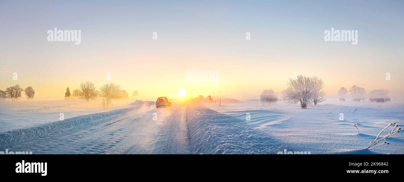 Panorama-Winterlandschaft mit verschneiten Straßen und einbahnigen Autos auf dem Land am frostigen frühen Morgen. Estland Stockfoto