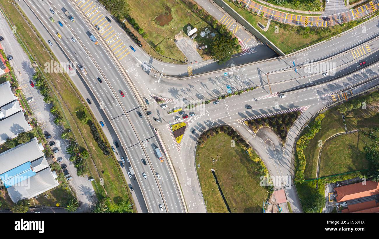 Luftaufnahme direkt über einer Autobahnausfahrt. Blick von oben auf Asphaltstraße führt durch das Feld und Wald. Antenne. Limousine Autos fahren auf der Autobahn. Bis Stockfoto