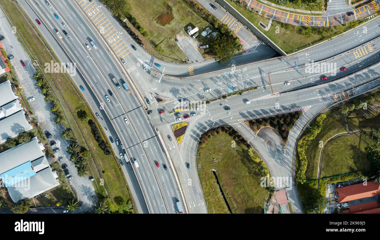 Luftaufnahme direkt über einer Autobahnausfahrt. Blick von oben auf Asphaltstraße führt durch das Feld und Wald. Antenne. Limousine Autos fahren auf der Autobahn. Bis Stockfoto
