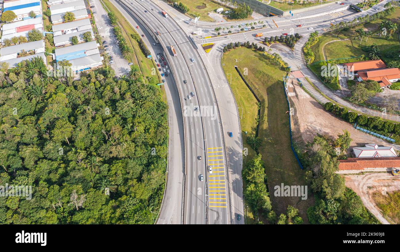 Luftaufnahme direkt über einer Autobahnausfahrt. Blick von oben auf Asphaltstraße führt durch das Feld und Wald. Antenne. Limousine Autos fahren auf der Autobahn. Bis Stockfoto