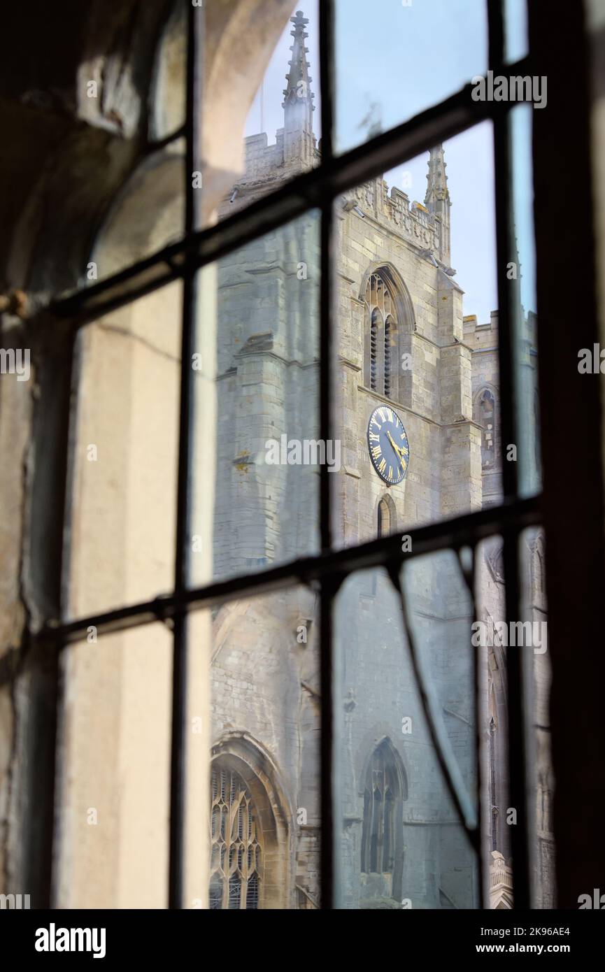 Blick auf den Uhrturm des Minsters von King's Lynn, die Priory Church of Saint Margaret durch ein altes, vielfarbiges Fenster des Rathauses, Großbritannien Stockfoto