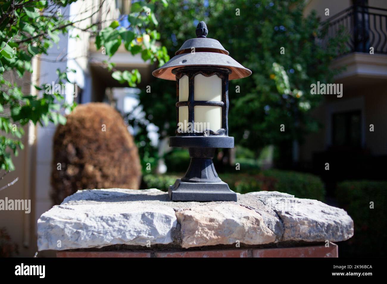 Alte alte alte Straßenlaterne auf einem Ziegelzaun im Garten. Metallic-Laterne im Retro-Stil. Straßenbeleuchtung. Stockfoto
