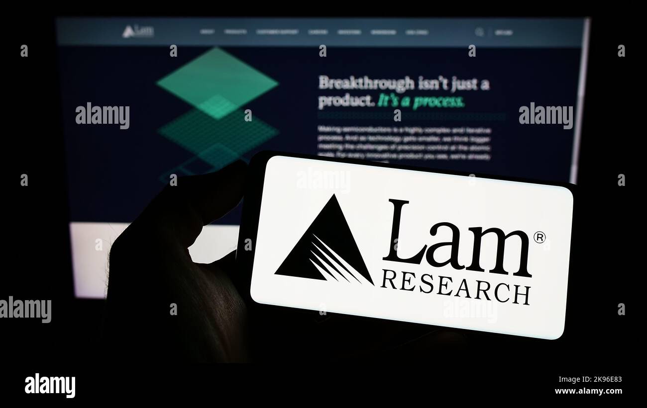 Person mit Mobiltelefon und Logo des US-Halbleiterunternehmens Lam Research Corporation auf dem Bildschirm vor der Webseite. Konzentrieren Sie sich auf die Telefonanzeige. Stockfoto