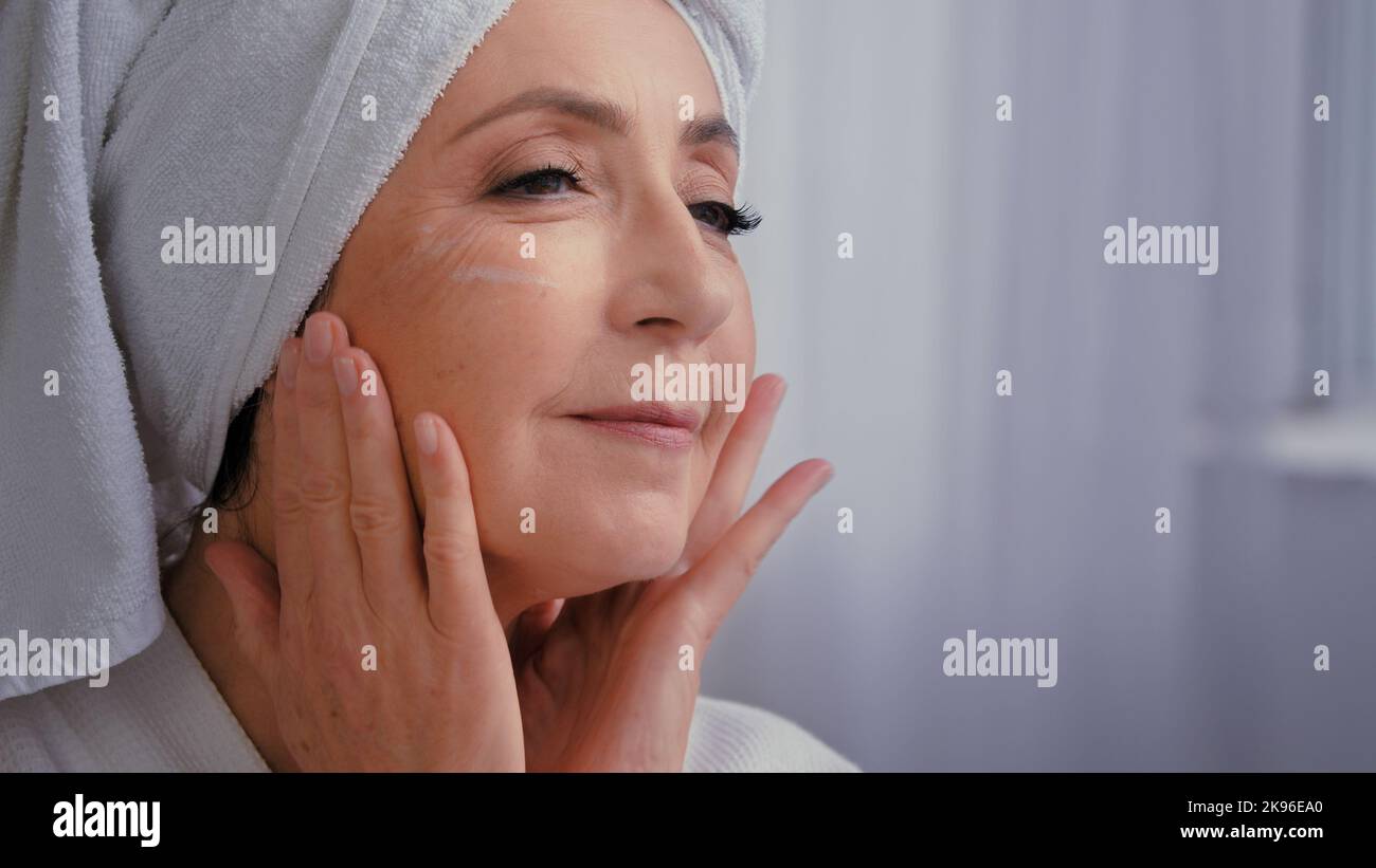 Alte ältere ältere kaukasische Frau berühren Massage weibliche faltige Gesicht Anwendung Anti Falten Alter Schutz Hautpflege-Creme Nahaufnahme 60s Dame Großmutter Stockfoto