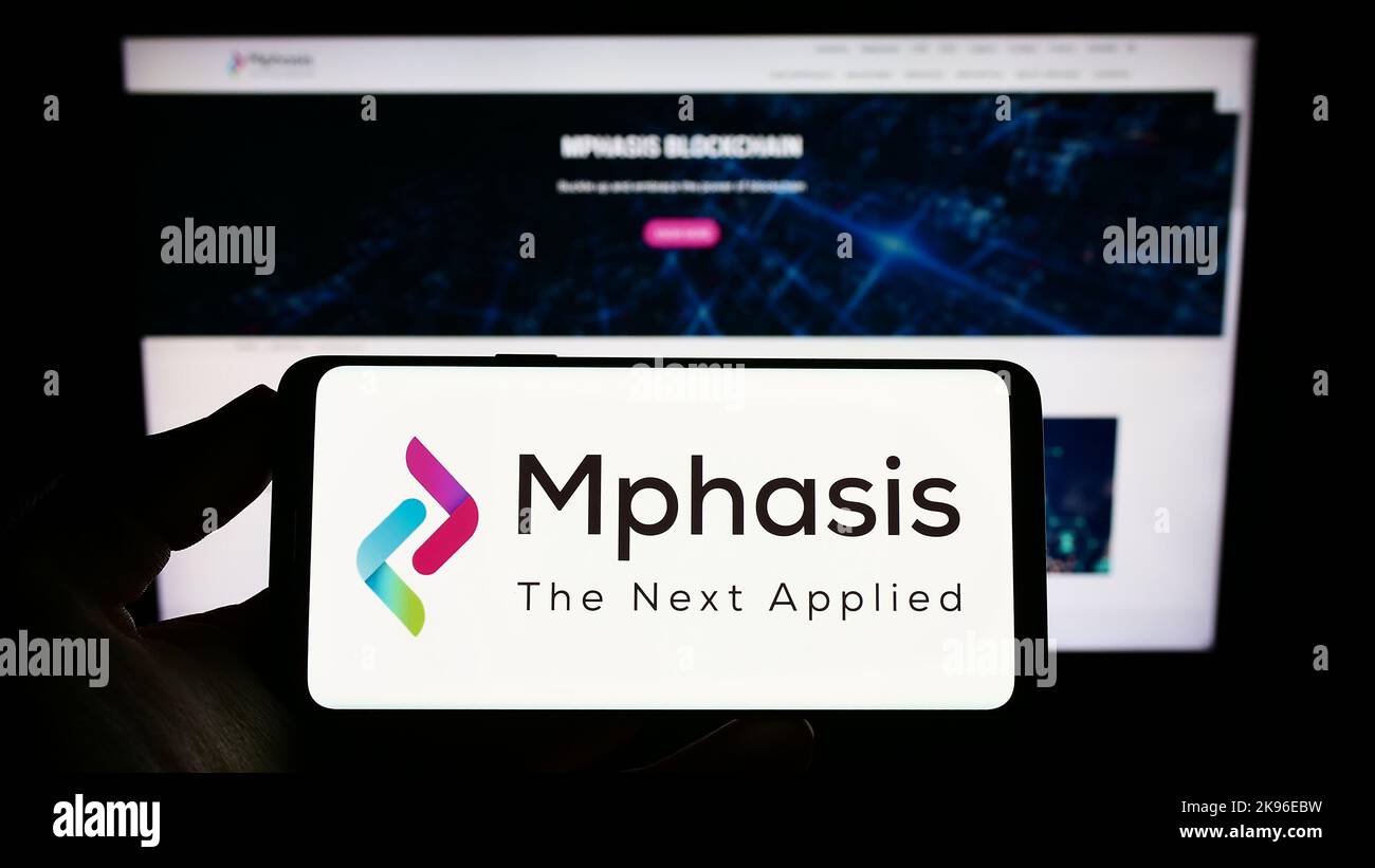 Person, die das Smartphone mit dem Logo des IT-Unternehmens Mphasis Limited auf dem Bildschirm vor der Website hält. Konzentrieren Sie sich auf die Telefonanzeige. Stockfoto