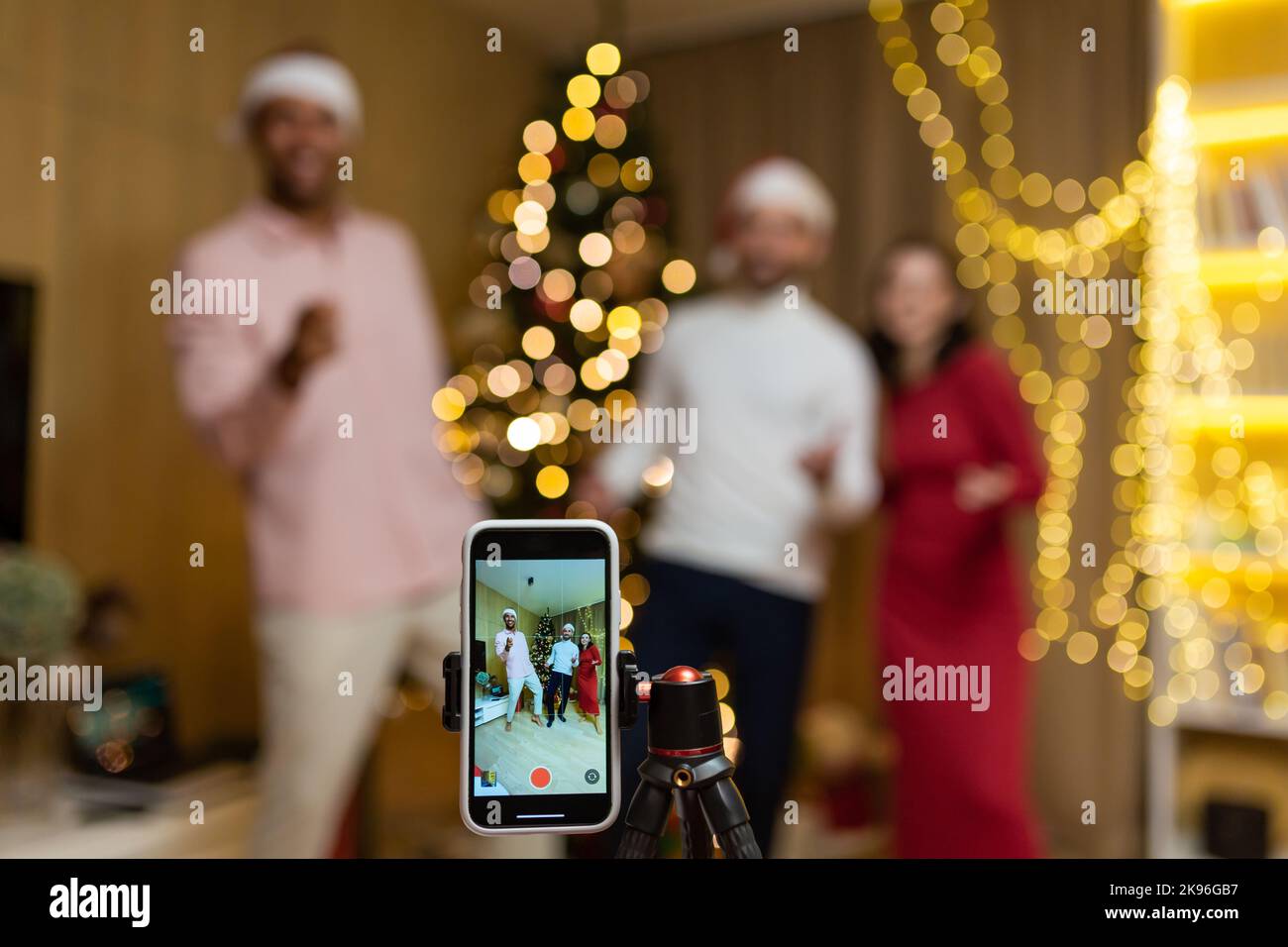 Lustige Freunde record reels Geschichten Front Smartphone Kamera für soziale Netzwerke während der Silvesterfeier Heiligabend Feier. Mit Spaß tanzen Blick Pose bei der Kamera zu Hause Jungs Spaß haben Stockfoto