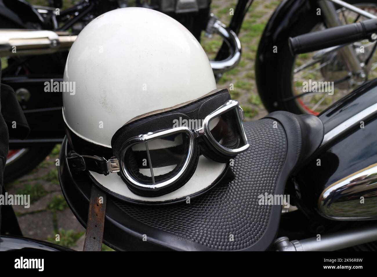 Vintage Crashhelm und Schutzbrille auf Motorradsitz Stockfoto