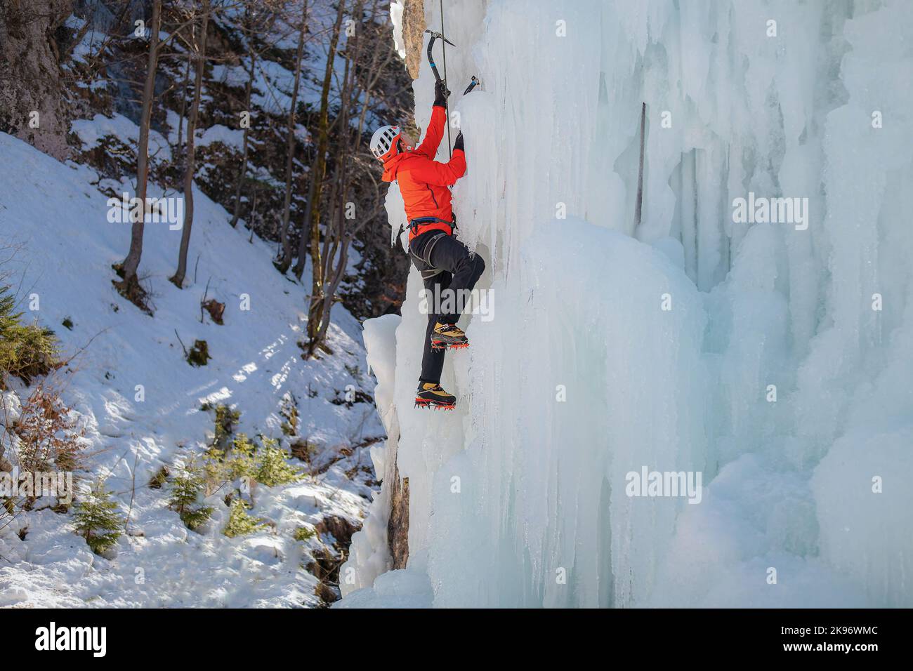 Alpinist Mann mit Eiskletterausrüstung auf einem gefrorenen Wasserfall Stockfoto