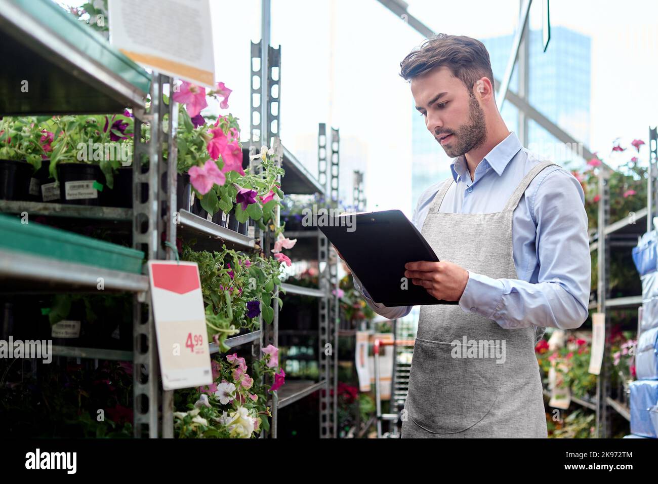 Floristin mit Zwischenablage, die in der Nähe eines Blumenregals steht. Stockfoto