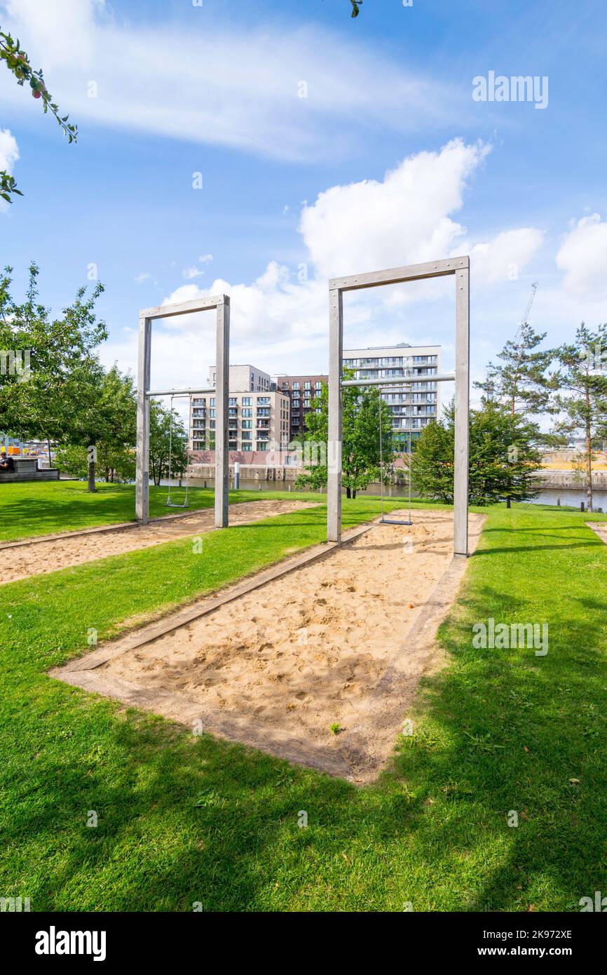 Überhöhene urige Schaukeln auf einem Spielplatz im Baakenpark in Hamburg, HafenCity. Eine mit Holzbalken umrandete Sandfläche dient als Fallschutz. Der Stockfoto