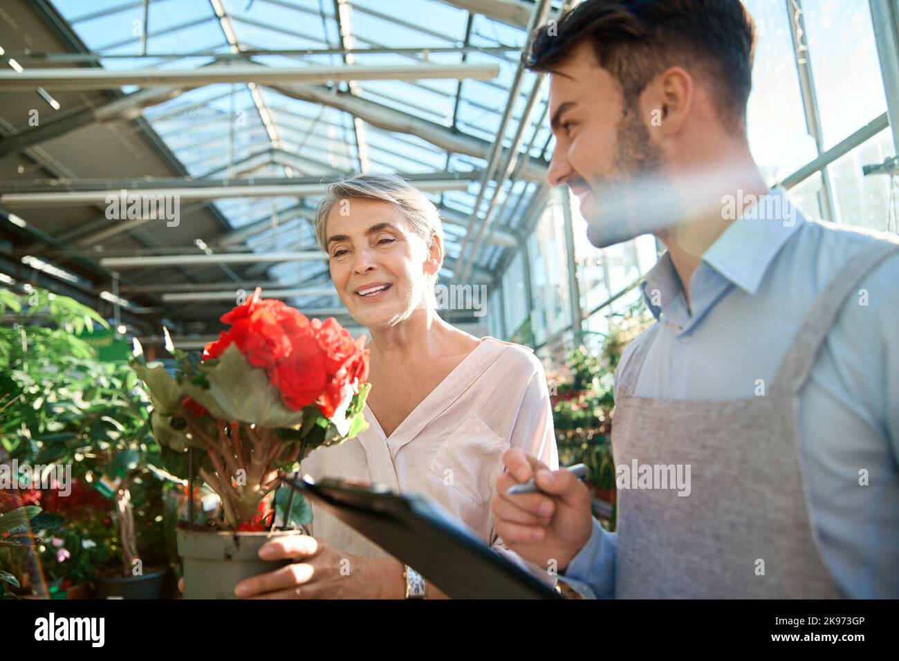 verkäuferin ist Floristin und ein glücklicher Käufer mit einer Pflanze in den Händen. Stockfoto