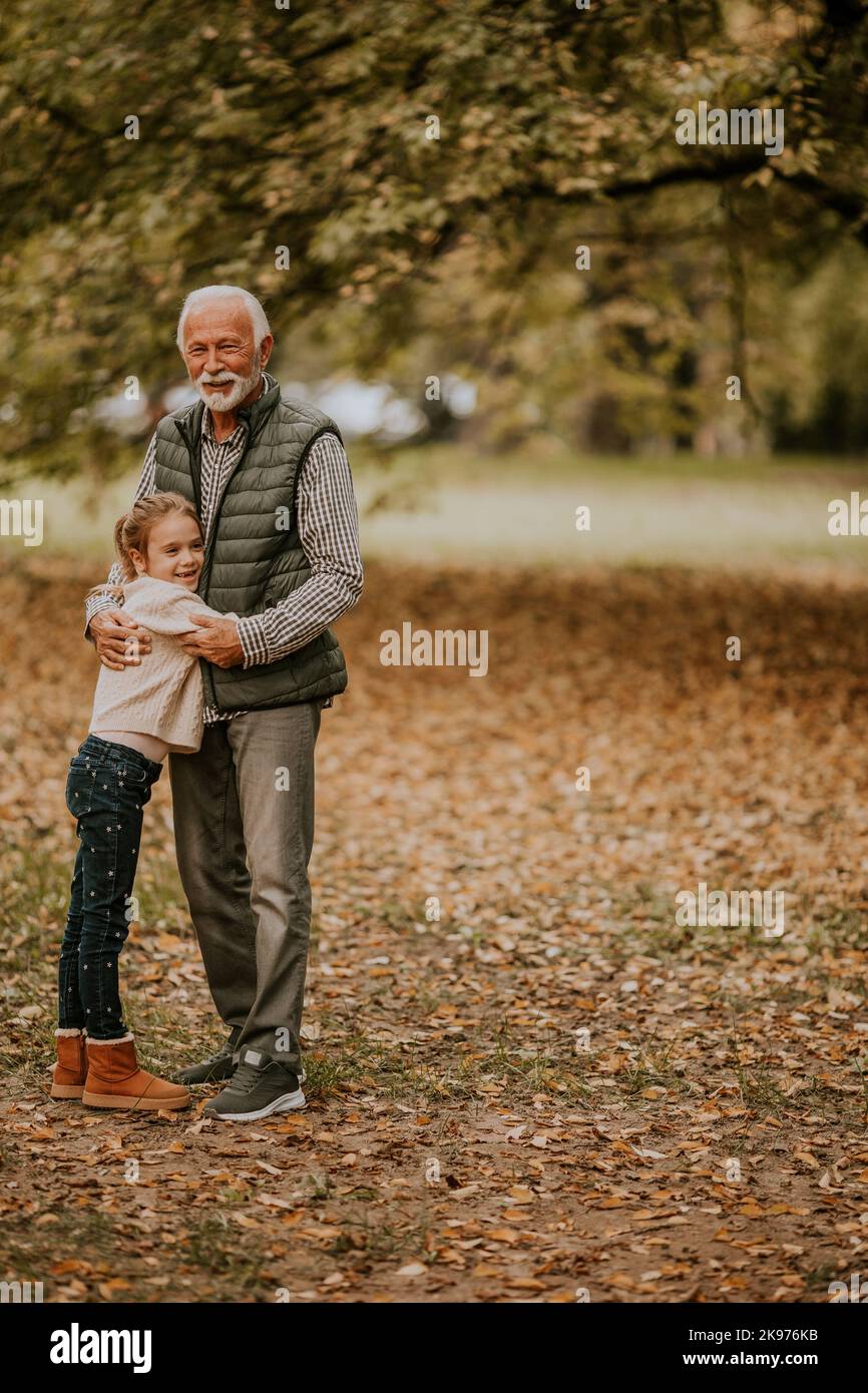 Der gutaussehende Großvater verbringt am Herbsttag Zeit mit seiner Enkelin im Park Stockfoto