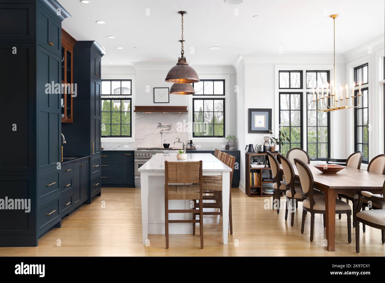 Eine luxuriöse Küche mit blauen Schränken, bronzefarbenen Deckenleuchten über der großen weißen Insel und luxuriösen Geräten. Stockfoto