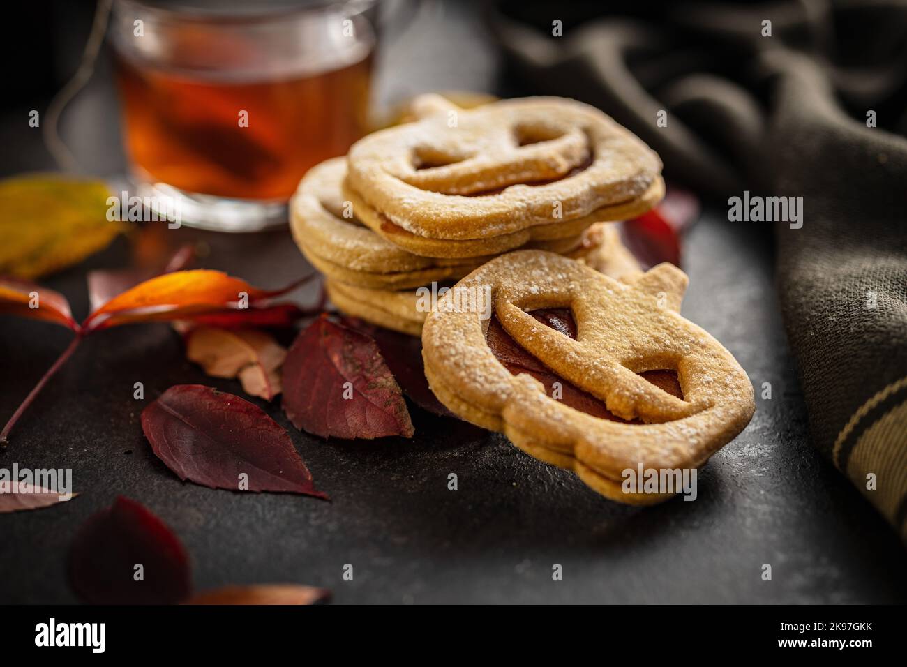 Linzer Kekse in Form eines Halloween Kürbisses auf dem schwarzen Tisch. Stockfoto