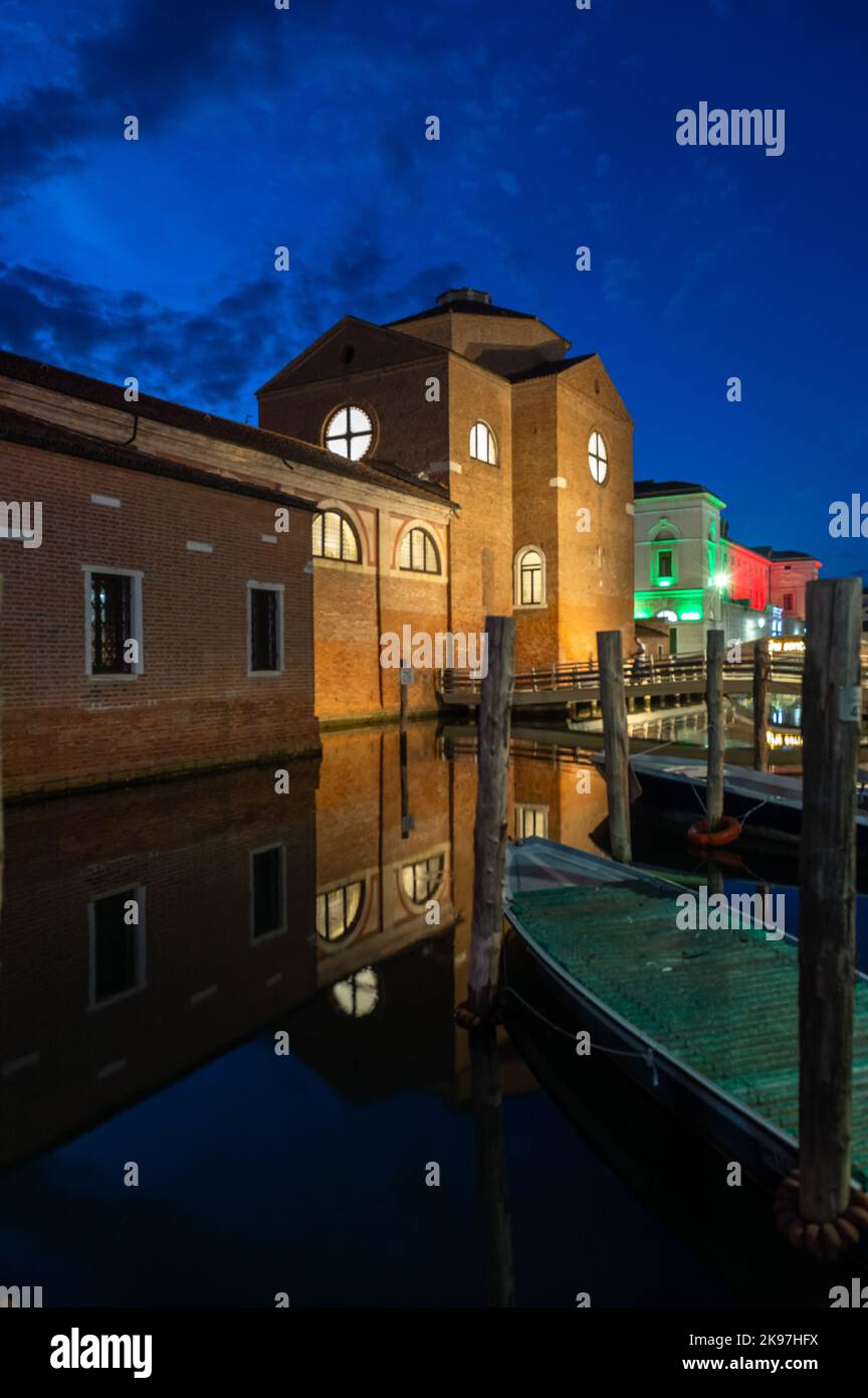 Chioggia, Italien. 20. August 2022. Allgemeiner Blick auf die Kanäle von Chioogia (Spitzname „Klein-Venedig“) mit den Booten und Gebäuden, die sich in der Dämmerung im Wasser unter dem künstlichen Licht spiegeln. Chioggia, eine Stadt in der venezianischen Lagune, die viele Touristen beherbergt, die Venedig besuchen, wurde nicht in den venezianischen Stadtkern aufgenommen. Touristen, die dort bleiben, müssen die Steuer jedes Mal zahlen, wenn sie Venedig ab dem 16. Januar 2023 besuchen. (Foto: Laurent Coust/SOPA Images/Sipa USA) Quelle: SIPA USA/Alamy Live News Stockfoto