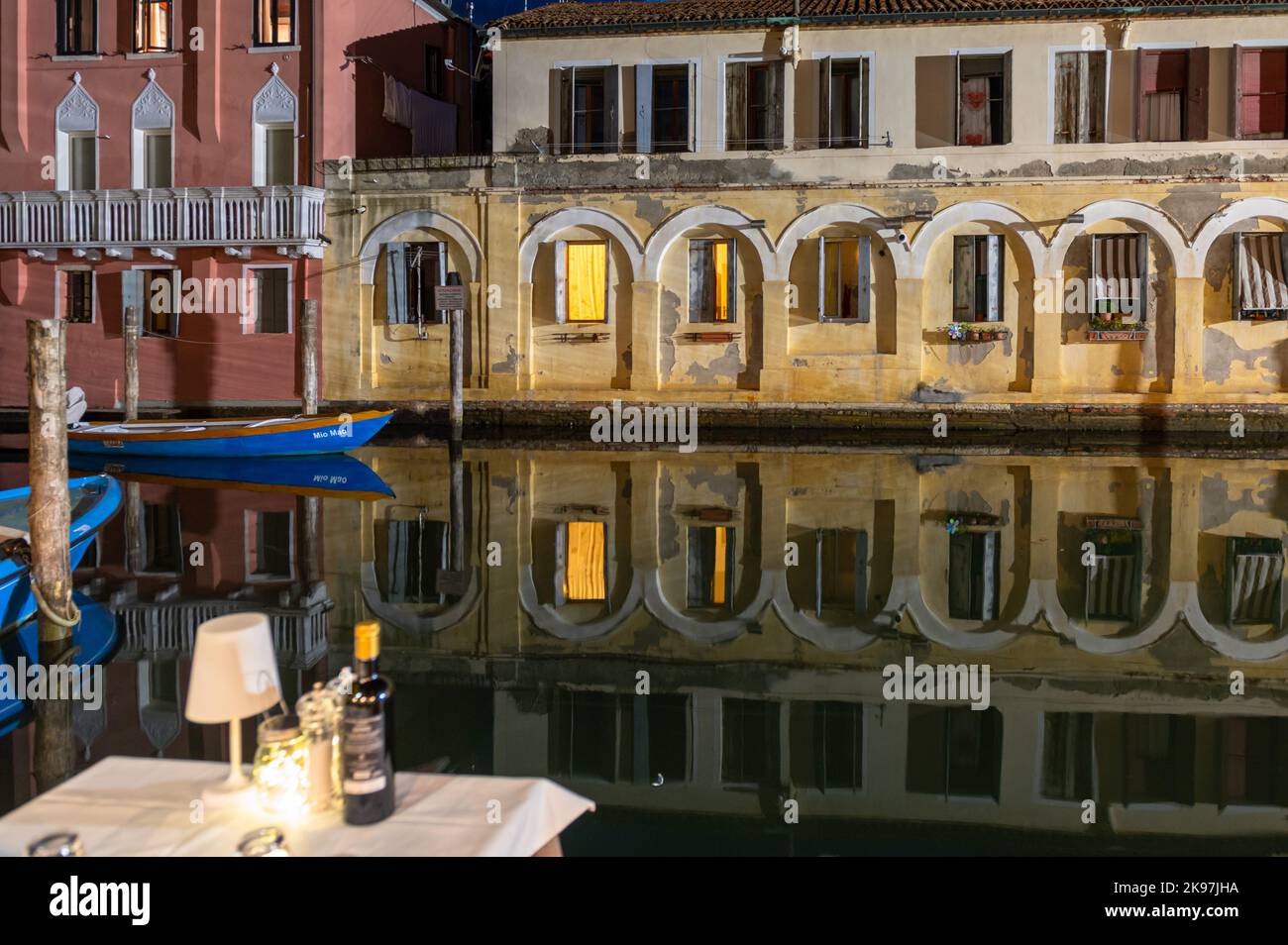 20. August 2022, chioggia, Italien: Gesamtansicht der Kanäle von Chioogia (Spitzname ''Klein-Venedig'') mit den Booten und Gebäuden, die sich in der Dämmerung im Wasser unter dem künstlichen Licht spiegeln. Chioggia, eine Stadt in der venezianischen Lagune, die viele Touristen beherbergt, die Venedig besuchen, wurde nicht in den venezianischen Stadtkern aufgenommen. Touristen, die dort bleiben, müssen die Steuer jedes Mal zahlen, wenn sie Venedig ab dem 16. Januar 2023 besuchen. (Bild: © Laurent Coust/SOPA Images via ZUMA Press Wire) Stockfoto