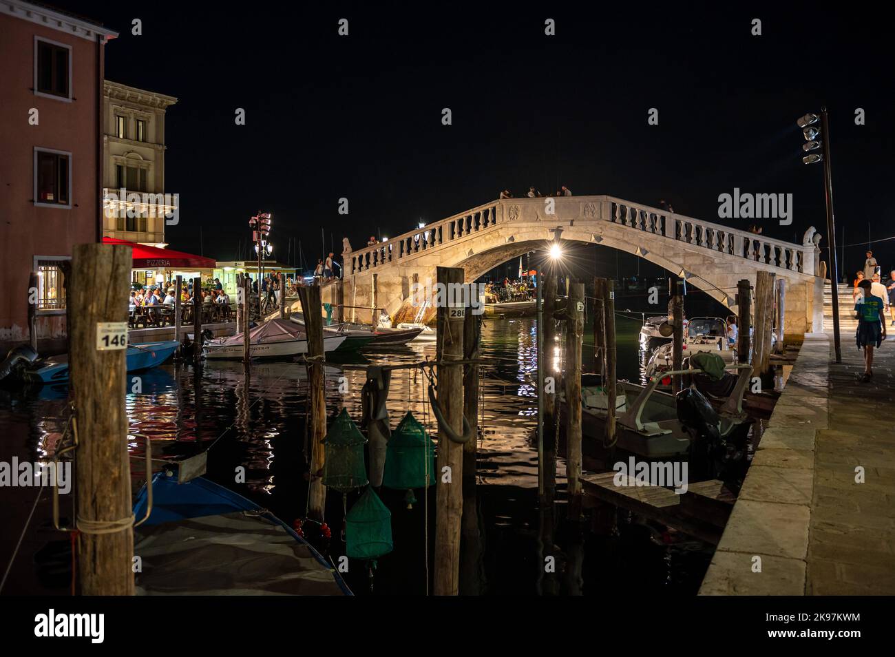 20. August 2022, chioggia, Italien: Gesamtansicht der Kanäle von Chioogia (Spitzname ''Klein-Venedig'') mit den Booten und Gebäuden, die sich in der Dämmerung im Wasser unter dem künstlichen Licht spiegeln. Chioggia, eine Stadt in der venezianischen Lagune, die viele Touristen beherbergt, die Venedig besuchen, wurde nicht in den venezianischen Stadtkern aufgenommen. Touristen, die dort bleiben, müssen die Steuer jedes Mal zahlen, wenn sie Venedig ab dem 16. Januar 2023 besuchen. (Bild: © Laurent Coust/SOPA Images via ZUMA Press Wire) Stockfoto