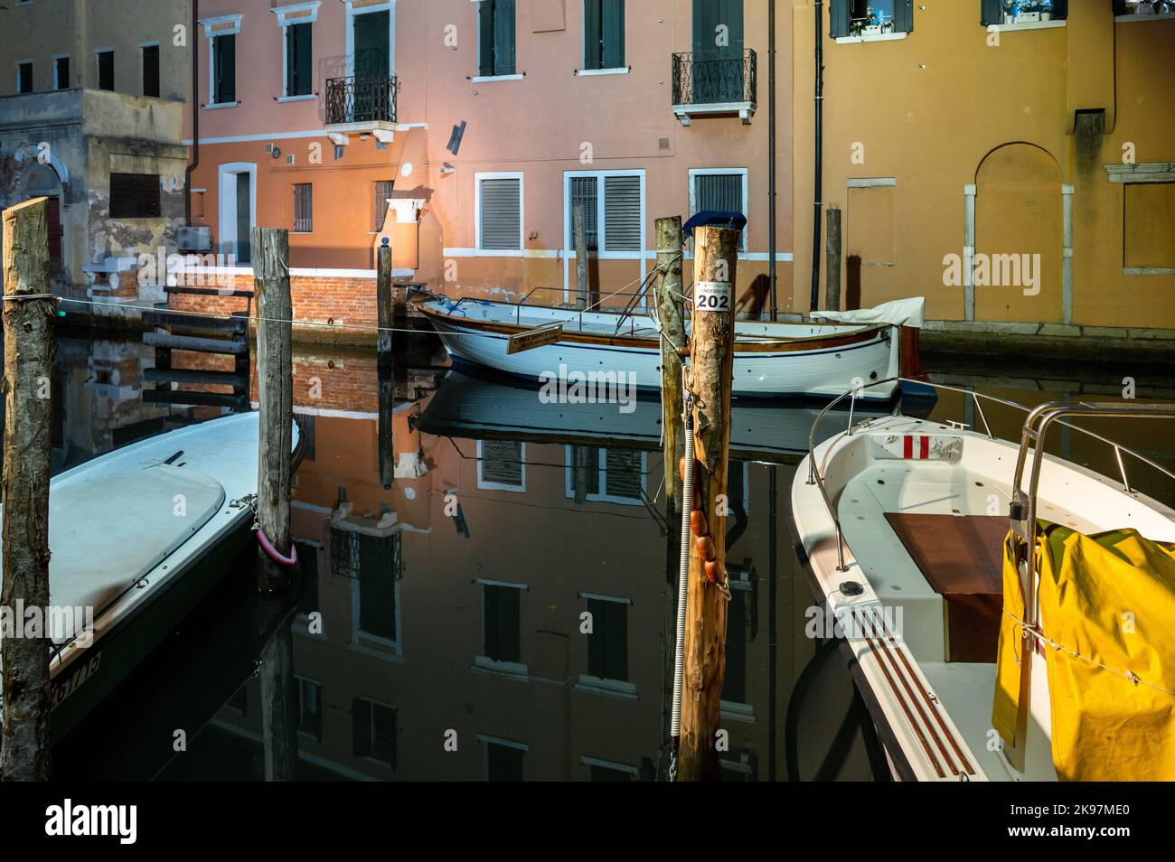 20. August 2022, chioggia, Italien: Gesamtansicht der Kanäle von Chioogia (Spitzname ''Klein-Venedig'') mit den Booten und Gebäuden, die sich in der Dämmerung im Wasser unter dem künstlichen Licht spiegeln. Chioggia, eine Stadt in der venezianischen Lagune, die viele Touristen beherbergt, die Venedig besuchen, wurde nicht in den venezianischen Stadtkern aufgenommen. Touristen, die dort bleiben, müssen die Steuer jedes Mal zahlen, wenn sie Venedig ab dem 16. Januar 2023 besuchen. (Bild: © Laurent Coust/SOPA Images via ZUMA Press Wire) Stockfoto