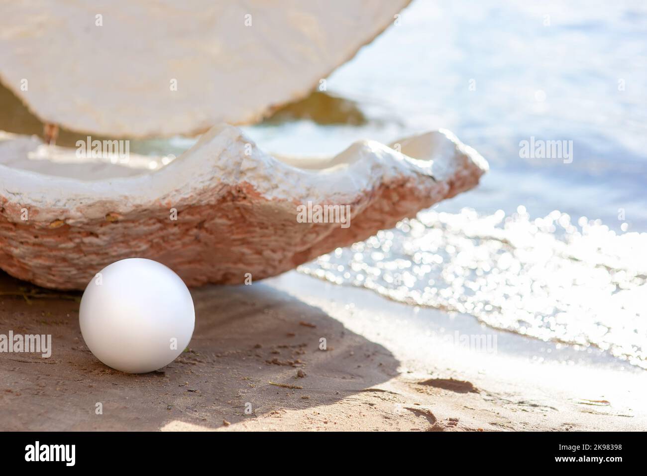 Dekorative offene große Muschel und eine große weiße Perle, an einem sonnigen Tag am Strand Stockfoto