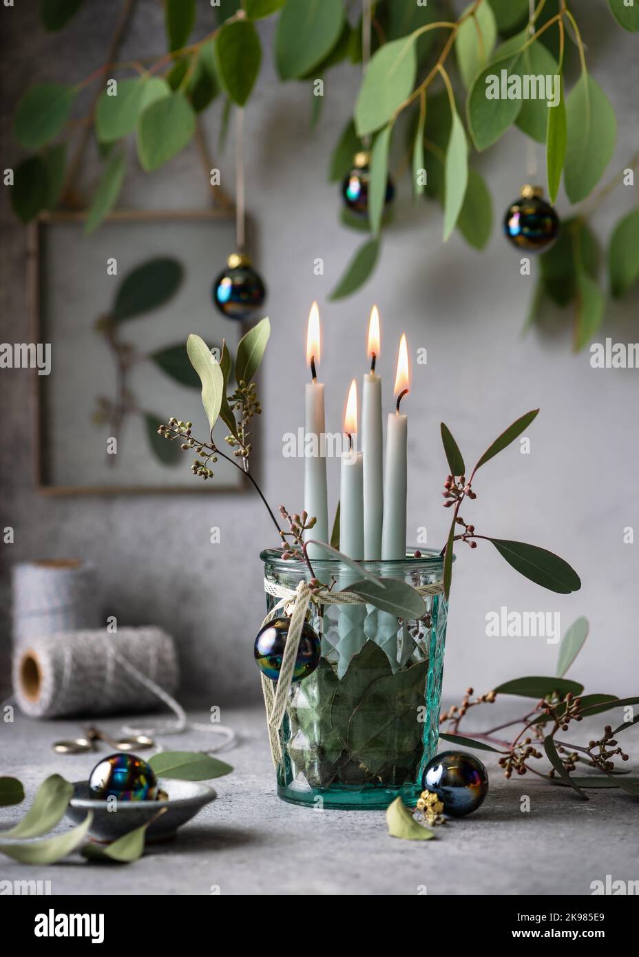 4. Advent. Weihnachtsdekorationen mit hellen minzfarbenen Adventskerzen und Eukalyptusblättern. Stockfoto