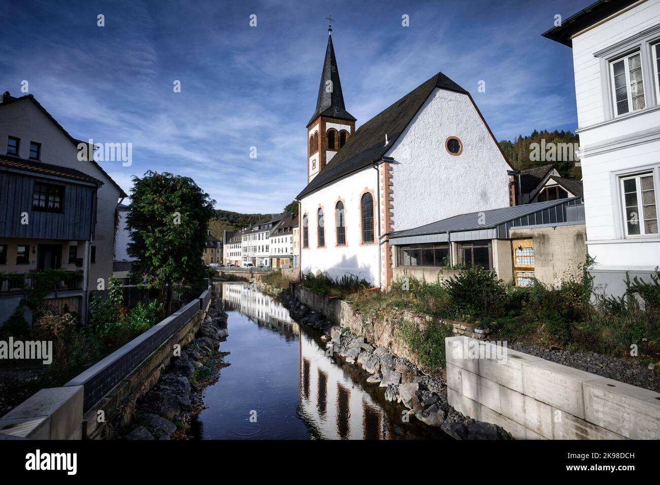 Die romantische evangelische dreifaltigkeitskirche spiegelt sich in der urft in der eifelstadt gemuend wider Stockfoto